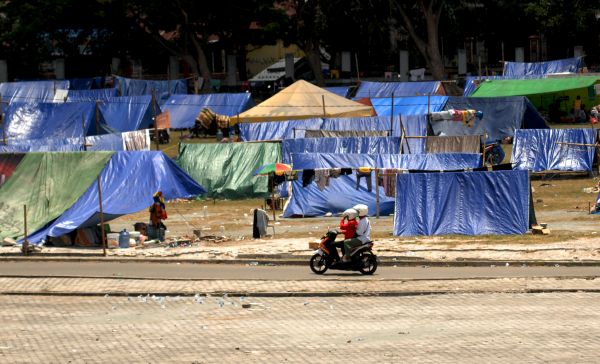 Warga korban gempa melintas di sekitar tenda pengungsian di halaman Masjid Agung, Palu, Sulawesi Tengah, Sabtu (6/10)
